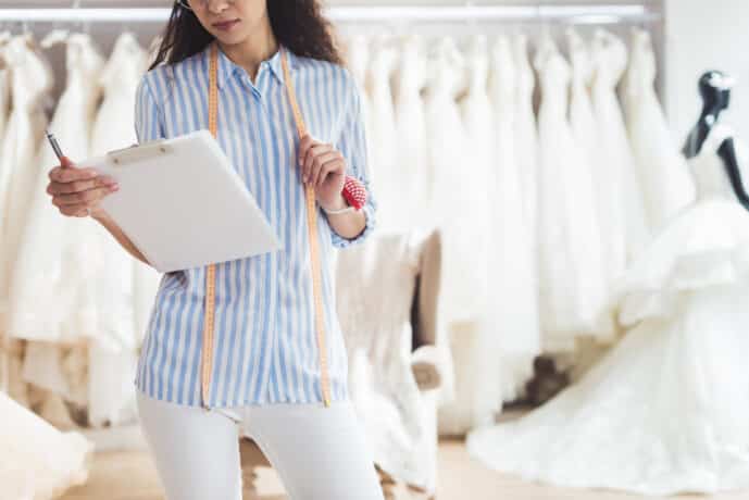 professional needlewoman holding clipboard in wedding fashion shop